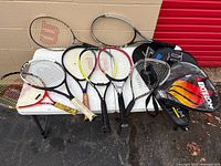 All nine racquets and two covers on folding table