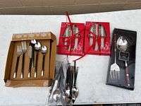 Group view of boxed flatware set, steak knife sets, serving set, and loose utensils