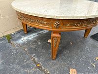 Front view showing carved wood base, floral gilt details and one leg