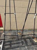 Front view of both black metal easels standing side by side showing overall structure