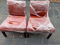 Front view of two rust fabric armless dining chairs wrapped in plastic