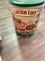 Exterior of green-lid tin labeled The Original Lincoln Logs