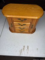closed light oak jewelry armoire on table