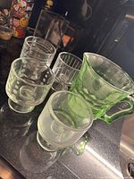 Group view of green pitcher and four footed tumblers