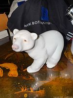 Front and side view of white porcelain polar bear figurine on table