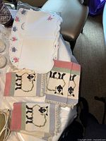 Stack of embroidered placemats and three visible sheep towels
