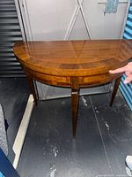 Top and front view of demilune table showing wood grain, scratches, tapered legs