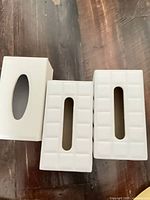 Top view showing three white tissue box covers, two quilted, one smooth