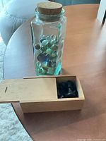 Glass jar filled with marbles beside wooden box of chess pieces