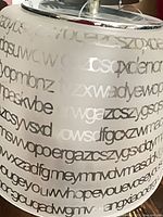 Close-up of frosted glass pendant shade showing etched alphabet pattern