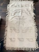 full view of rectangular cream rug with fringe and geometric pattern