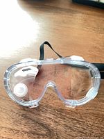 Unwrapped clear lab safety goggles showing lens, frame, and strap