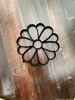 Front view of black flower-shaped scarf hanger on wood surface