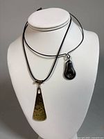 Pendant on leather cords displayed on bust