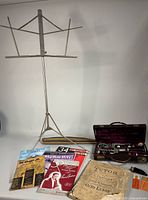 Full lot view: clarinet case open, folding music stand, books