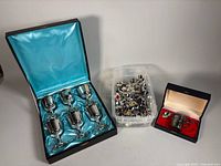 Group shot of goblets in case, bin of spoons, child’s cup and spoon in case