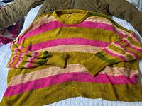 Striped acrylic sweater laid flat over jacket