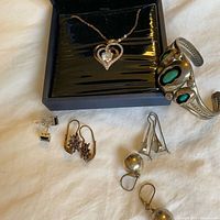 All jewellery pieces laid out: pendant in box, cuff bracelet, multiple earring pairs