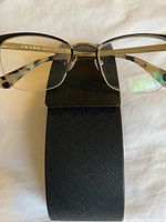 Front view of Prada frames resting on case, shows frame style and size markings