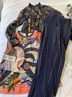 Three garments laid flat: floral blouse, printed top, pinstripe pants