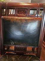 Chair back showing carved mahogany frame and leather panel