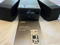 Front view of receiver with two speakers, remote and manual visible