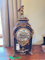Front view of ornate French-style mantel clock showing dial, ormolu mounts and pendulum