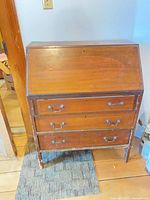 Front view of closed desk showing drawers and slant front