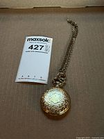 Pocket watch with chain on cardboard surface