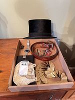 Tray showing jewellery, belt, watch, purse, and black top hat in background