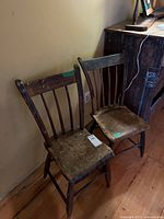 Front view of both wooden spindle-back chairs showing overall design and wear