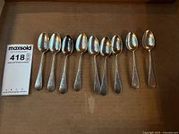 Nine sterling spoons laid out bowl up