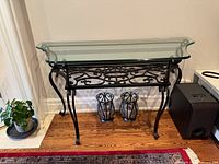 Front view of glass console table on iron base with two metal holders underneath