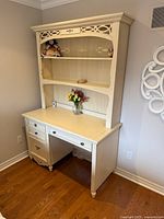 Front view of white desk with attached hutch showing drawers, shelves and decorative trim