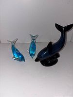 Group view of two glass dolphins and one ceramic dolphin