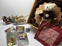 Overview of lot showing boxed plush bear, resin sleigh figurine, BearWear packaged pins, red quilted fabric