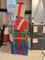 Full view of stacked glittered gift boxes showing colors, ribbons and overall height.