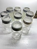 Group of nine clear glass canning jars with lids