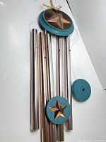 Full view of wind chime showing tubes, teal discs, bronze star, hanging loop