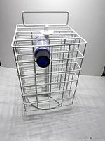 Front view of white metal rotating paint organizer showing grid structure, handle, spinning base