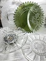 Group of all five glass serving pieces including green dish, divided tray on chrome base, clear patterned plates