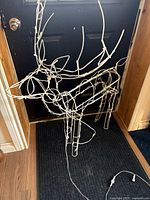 Full view of one reindeer frame showing white wire structure and rope lights with plug