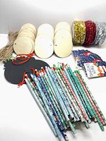 Group view of wooden discs, black ornaments, tinsel spools, pencils and gift tags