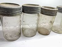 Front view of three jars showing embossed logos and zinc lids