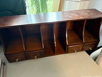 Front view showing four compartments and four drawers with brass pulls