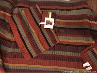Image of double bed bedspread and two matching pillow shams in multi-color striped pattern with rich warm colors.