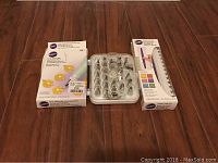 Photo of set of Wilton cake decorating tools: two 24-inch reusable silicone piping bags, a tray of assorted metal piping tips, and a plastic icing comb, all new in original packaging.