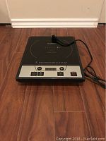 Front view of Berghoff induction burner cooktop placed on wooden floor, showing control panel and power cord.