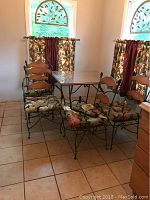 Dining table and 4 chairs with floral cushions positioned near windows with curtains.