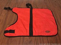 Red Breathe Comfort dog blanket laid flat on wood floor showing shape, size, black straps and edging with fabric texture.